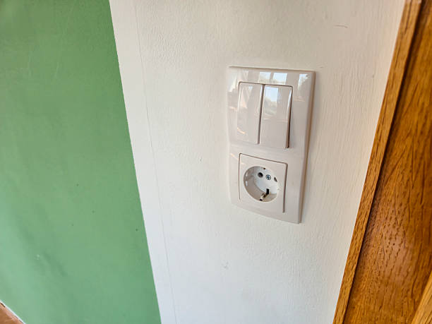 istock Close-up of a modern electrical socket and switch embedded in a white wall with a green accent. Ideal for articles on home improvement and electrical installations. 2223763962