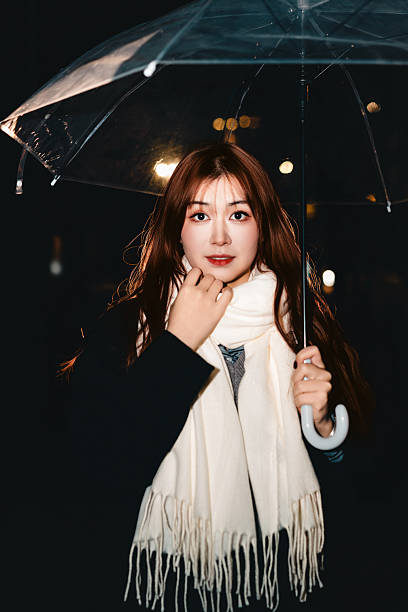 Young woman enjoying winter night outdoors, gently touching her scarf.
