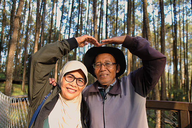 Smiling elderly couple sharing a joyful moment outdoors in a tranquil forest. Captures a bond of affection and the beauty of nature during relaxed recreation time. Yogyakarta is province in Indonesia