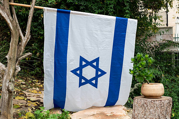 istock An Israeli flag hanging vertically on a tree outside a home on Independence Day in Jerusalem, Israel. 2223779672