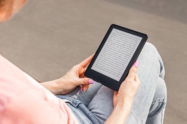 istock woman reading e-book sitting on bench, close-up. 2223783867