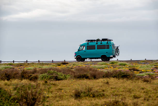 istock A blue van is driving down a road in a grassy field 2223785920
