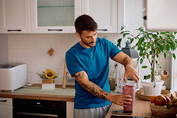 istock Mid adult man making fruit smoothie for breakfast in the kitchen. 2223786122