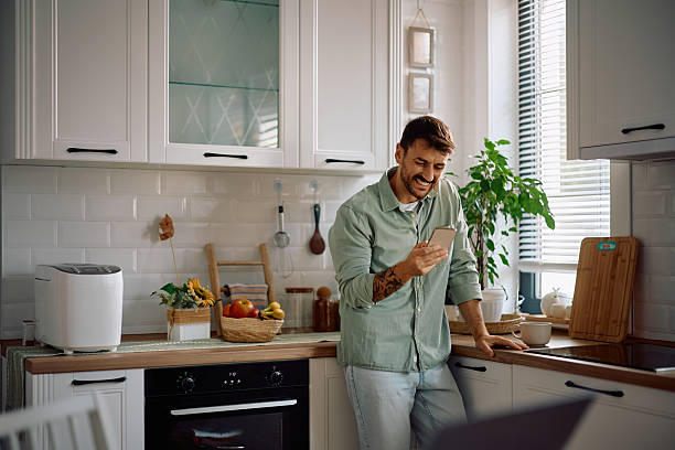 istock Happy man text messaging on cell phone in the kitchen. 2223786192