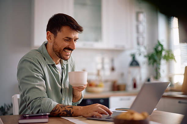 istock Happy man surfing the net on laptop while drinking coffee at home. 2223786217