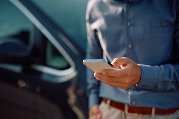 istock Close up of man using app on cell phone next to his car. 2223787695