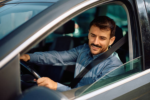 istock Happy man parking car in reverse while looking at side view mirror. 2223787713