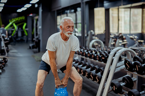 istock Fit Elderly Man Exercising With Kettlebell in Sport Center 2223799853