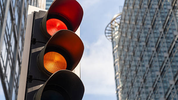 istock Red and amber traffic lights with modern office tower in background 2223801007