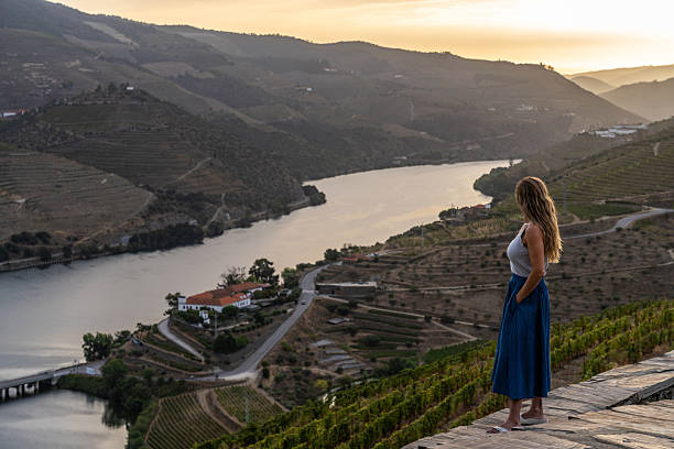A Portuguese woman on vacation and looking at the Douro Valley during a sunrise of summer.