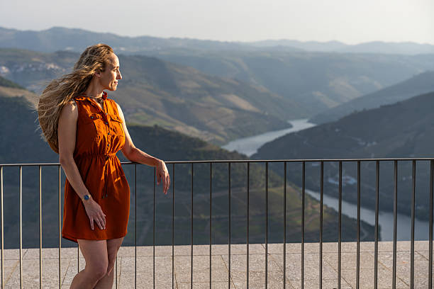A Portuguese woman on vacation and looking at the Douro Valley from the Miradouro Casal de Loivos during a sunset of summer.