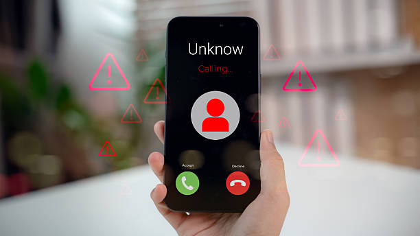 Hand holding smartphone showing unknown caller with red alert icons, representing phone scam, fraud warning, and digital communication threat.