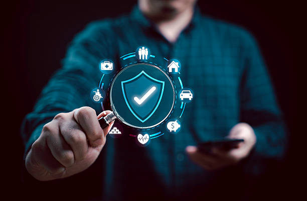 Businessman holds a magnifying glass with a shield icon for symbolizing security and protection in various aspects insurance of life including health, finance, and home.