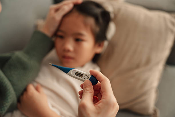 istock Worried Asian mom measuring her sick daughter's temperature while she rests in bed 2223804506