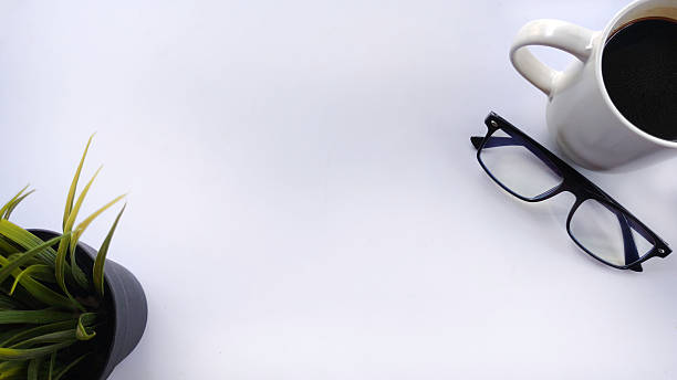 istock Minimalist flat lay workspace featuring plant, eyeglasses, and a cup of coffee on white. Ideal for business, planning, productivity, time management, daily agenda with ample copy space. 2223807440