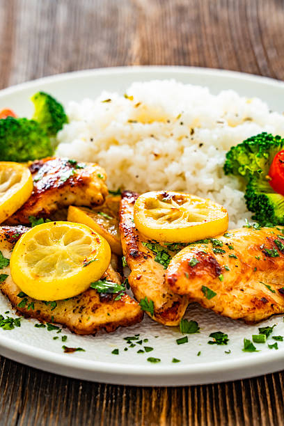 istock Lemon chicken escalopes with rice on wooden table 2223811556