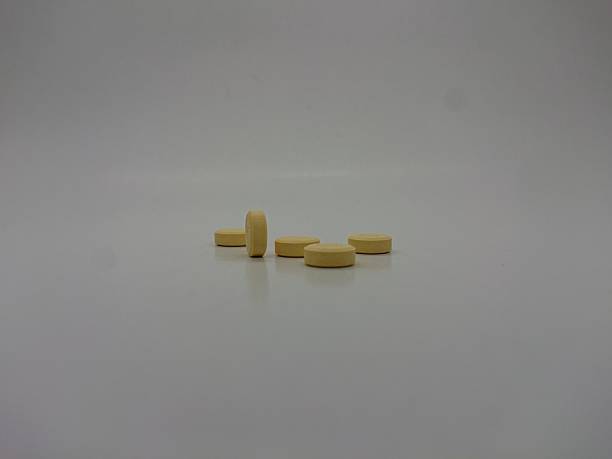 istock Close-up of several yellow pills on a white surface 2223811735