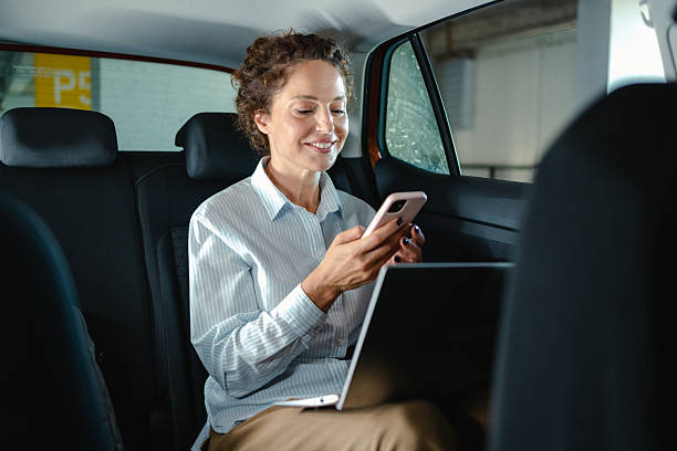 istock Woman using smartphone inside a car while working on a laptop 2223812153