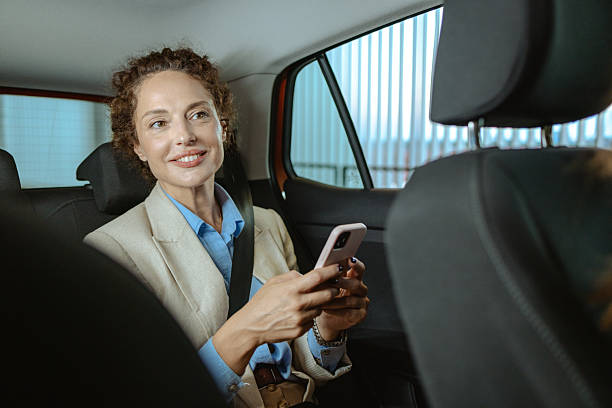 istock Businesswoman smiling and using a smartphone while traveling inside a car 2223812288