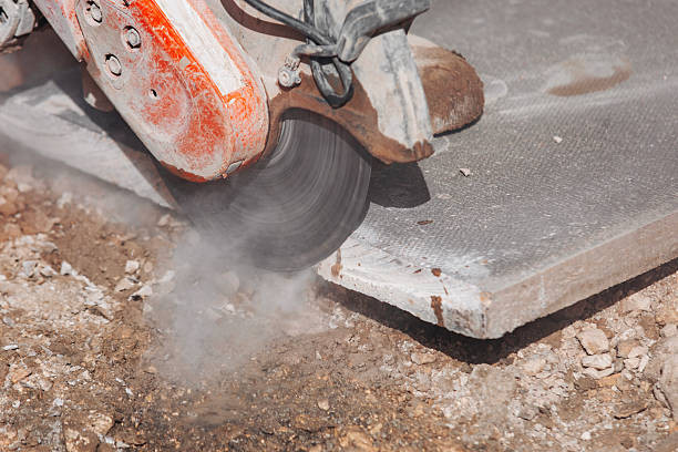 istock Builder cutting concrete paving slab with petrol concrete saw and a diamond blade during external footpath paving works close up 2223812360