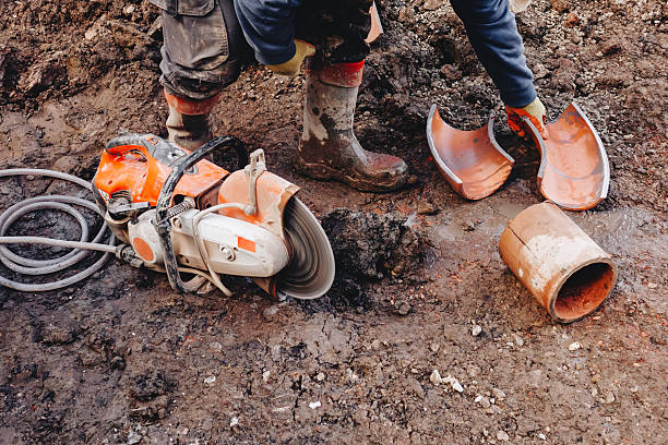 istock Construction worker cutting clay drainage pipes at building site with power saw and diamond blade 2223813877