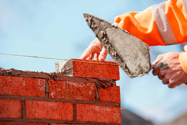 istock Close-up of skilled bricklayer working on construction site laying one more red brickin the wall 2223814356