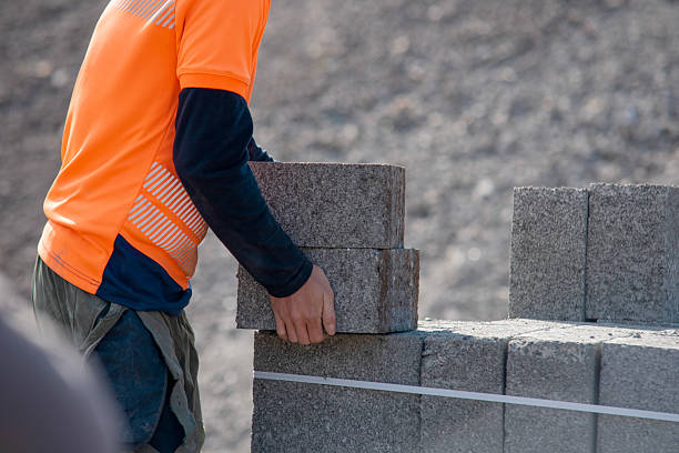 istock Example of manual lifting as bricklayers carrying concrete footing blocks in hand on building site 2223814357