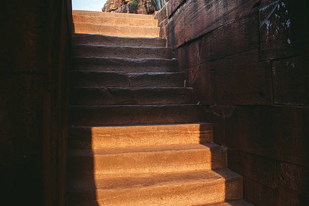 Old stone steps leading upward through an ancient structure in warm light.