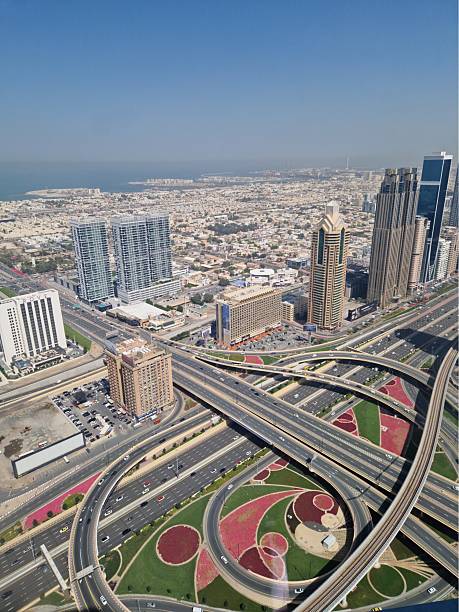 High-angle view of an intricate highway interchange surrounded by skyscrapers and residential buildings in Dubai, United Arab Emirates. The photo captures the vibrant urban planning, landscaped roadways, and infrastructure development of one of the world’s most advanced cities.