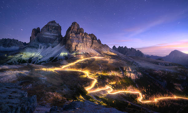 istock Car light trails on mountain road and high rocks at night 2223825992