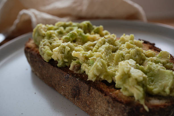 istock Slice of sourdough toast topped with mashed ripe avocado. 2223827311
