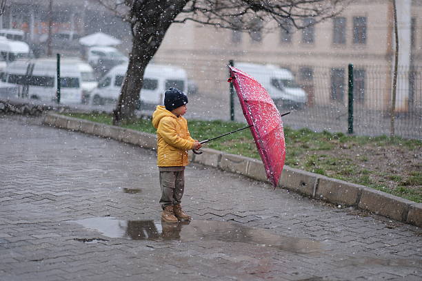 A little boy with umbrella spending time in the snowfall