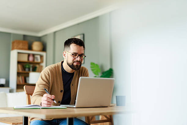 istock Young Professional In Tan Cardigan Working On Laptop In Bright Home Office Setting 2223829502