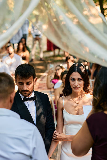 istock Bride and groom exchanging vows during wedding ceremony under white veil 2223832464
