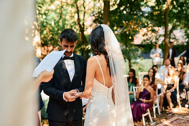 istock Bride putting ring on groom's finger during wedding ceremony in the woods 2223832674