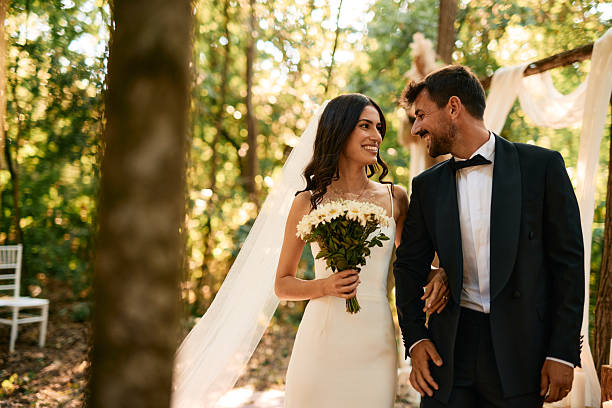 istock Bride and groom walking arm in arm in the forest 2223833054