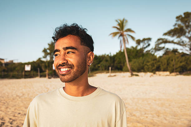 Portrait of a young tourist enjoying summer holidays on a tropical beach, smiling while soaking up the sun amidst palm trees and serene waves