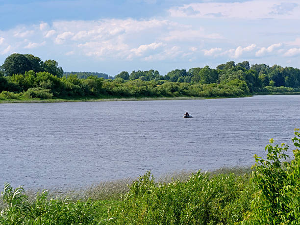Wide river with small fishing boat far away