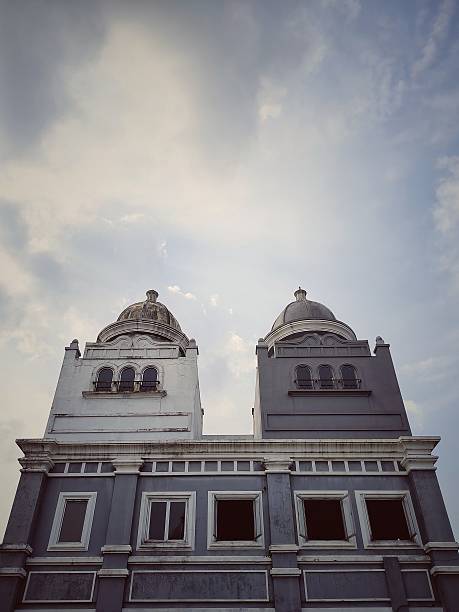 A vintage building with two prominent domes under a serene cloudy sky in public market area in South Tangerang, Indonesia, showcasing detailed architectural design and classic style.