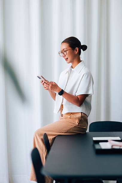 Woman Seated Indoors Using Smartphone in Modern Office Space