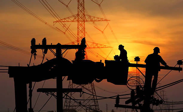 istock silhouette electric worker on crane with the high voltage electric pole  sun set nature background 2223875496