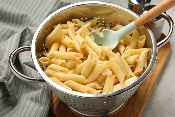 istock Delicious penne pasta in colander on table, closeup 2223877551