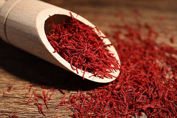 istock Aromatic saffron and scoop on wooden table, closeup 2223877552