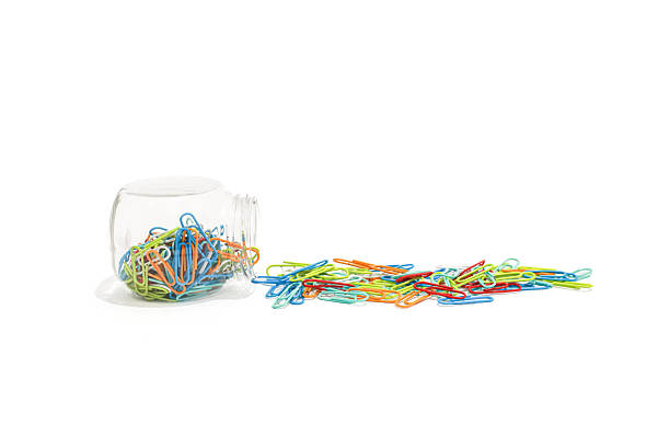 istock Vibrant multicolored paper clips spilling from a clear glass jar on a white surface 2223881795