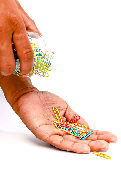 istock Hand Pouring Colorful Paper Clips from a Container on White Background 2223881831