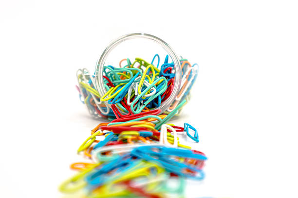 istock Colorful Paper Clips Spill from a Clear Container on a White Background 2223881973