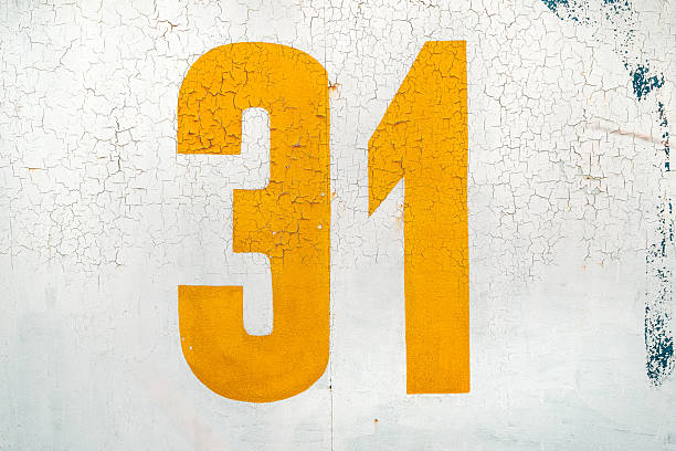 Yellow number thirty one on grunge white wall as background