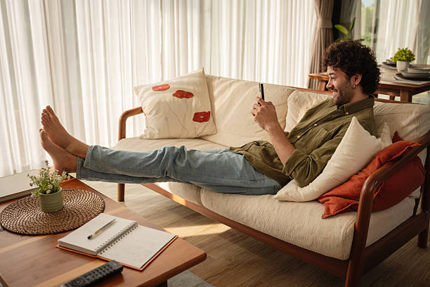 istock Young man relaxing on sofa with a phone 2223883101