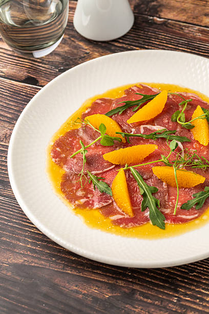 istock Thinly sliced beef carpaccio with orange segments and arugula leaves 2223884775