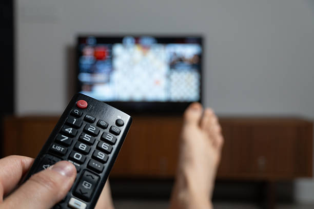 istock Man relaxing on sofa and watching television with remote control in hand 2223889537